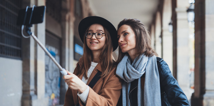 Smile girlfriends taking photo selfie on smartphone mobile. Blogger hipster travels in city. Holiday friendship concept. Travelers in glasses and hat self cellphone internet technology mockup space