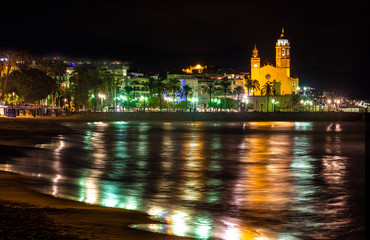 Fototapeta na wymiar coastal town at night with lighting on the promenade and church in the background - image