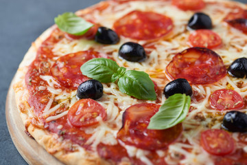 Pizza with chorizo, mozzarella cheese, cherry tomatoes, black olives and oregano. Home made food. Concept for a tasty and hearty meal. Close up.  