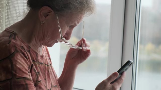 Elderly woman with vision problems trying to make out a message on a smartphone