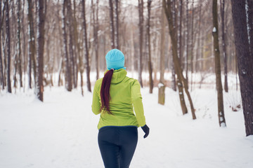 Photo on back of young athlete girl running in winter park