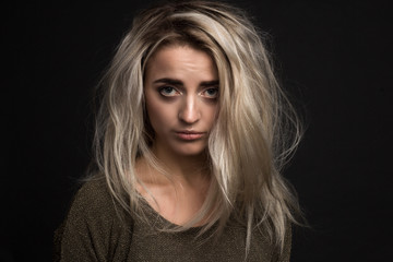 portrait of a young beautiful girl with an offended expression and disheveled hair on a black...