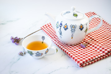 Cup of tea and teapot on red tablecloth, english tea