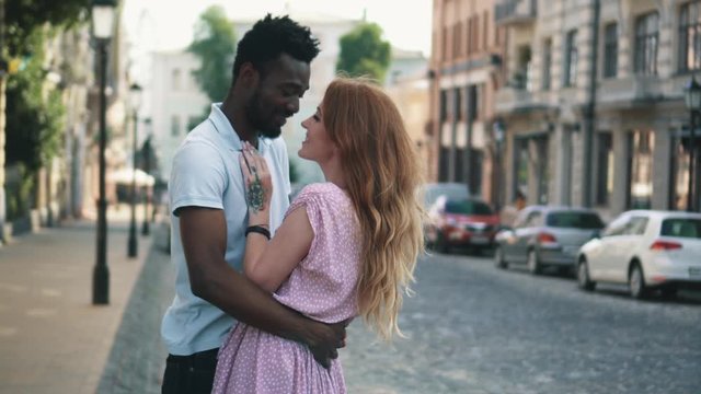 Young couple in love standing and tenderly cuddling on streets of European cities
