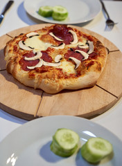 Selbstgemachte Pizza auf Holzbrett mit Salami und Pilzen lecker