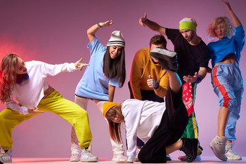 Hip hop battle in spacious dance hall, young people dancing break dance, pretty sportive girl in white hoodie and black loose pants showing street dance movie - obrazy, fototapety, plakaty