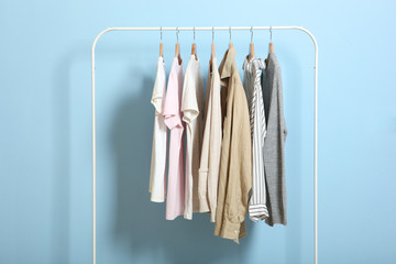 fashionable clothes on hangers on a wardrobe rack on a colored background.