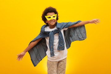 Portrait of a young, mixed race boy dressed as a superhero. Black baby in super hero costume. The winner and success concept.