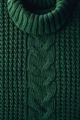 Knitted texture background of a winter green high neck sweater. Hipset style. Christmas traditions.