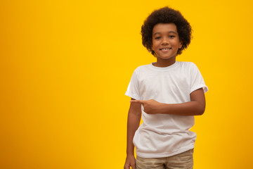 African American boy with black power hair on yellow background. Smiling black kid with a black...