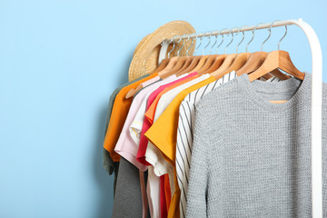 Obraz premium fashionable clothes on hangers on a wardrobe rack on a colored background.