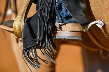 A closeup view on the cowboy boot with spur inside the stirrup