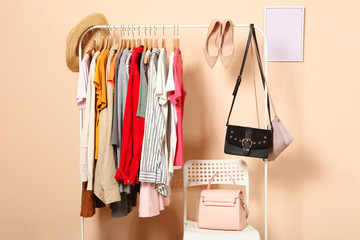 fashionable clothes on hangers on a wardrobe rack on a colored background.