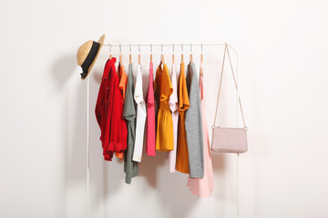Fototapeta Fashionable clothes on hangers on a wardrobe rack on a light background. obraz