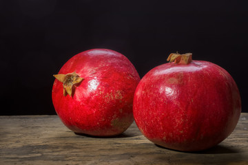 Fototapeta na wymiar Ripe pomegranate on a wooden board on a dark background