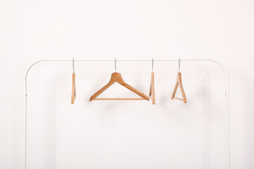 empty clothes hangers on a wardrobe rack on a light background.