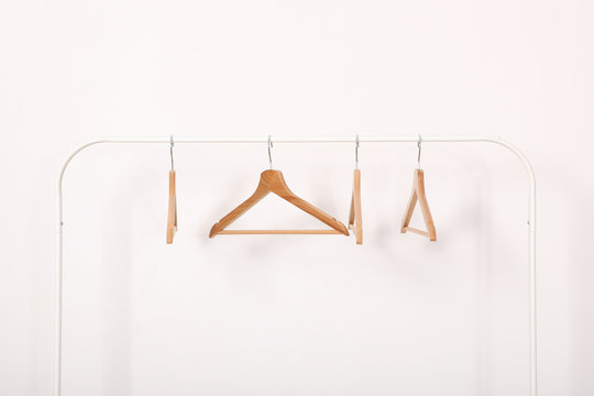 empty clothes hangers on a wardrobe rack on a light background.
