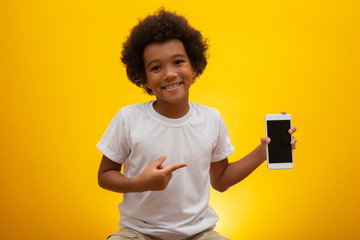 Excited boy smiling and poiting at white screen on smartphone.