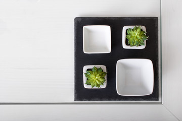 Black square plate with square dishes on white table background, top wiev