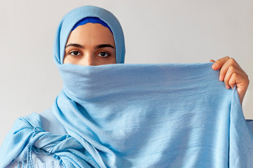 Beautiful muslim woman covers her face with bright blue cloth. Islamic fashion style