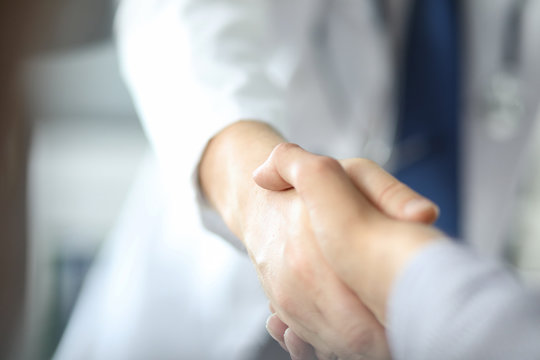 Closeup image of healthcare professional or doctor or dentist shaking hands with patient.
