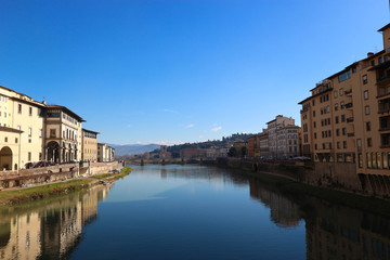 Fototapeta na wymiar scenic view to Arno river from ponte vecchio in florence italy with bright blue sky
