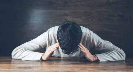 sad man hand on head on dark background