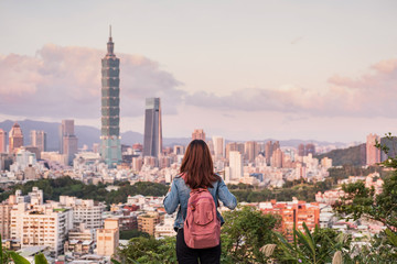 Fototapeta premium Young woman traveler looking beautiful cityscape at sunset in Taipei, Travel lifestyle concept