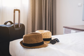 Travel luggage with hat on bed in the hotel room, Summer vacation concept
