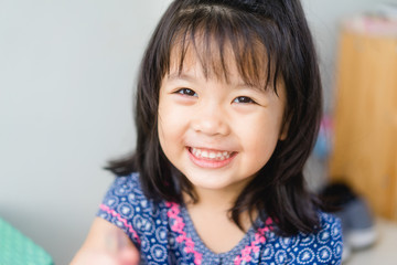 Happy Little asian girl child showing front teeth with big smile and laughing: Healthy happy funny smiling face young adorable lovely female kid.Joyful portrait of asian girl walking in playground.