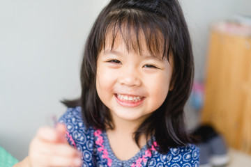 Happy Little asian girl child showing front teeth with big smile and laughing: Healthy happy funny...