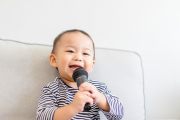 Baby 2 years old boy holding microphone and singing at home.Baby boy relax learn to sing in music...