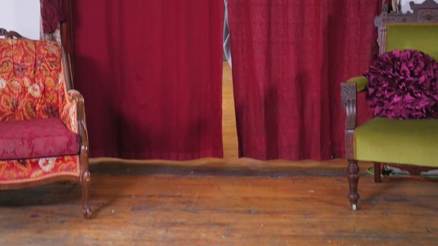 An Attractive Young Female Walking Through Two Red Curtains