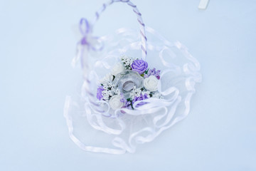 Engaging rings in a basket on a white table with purple and white flowers