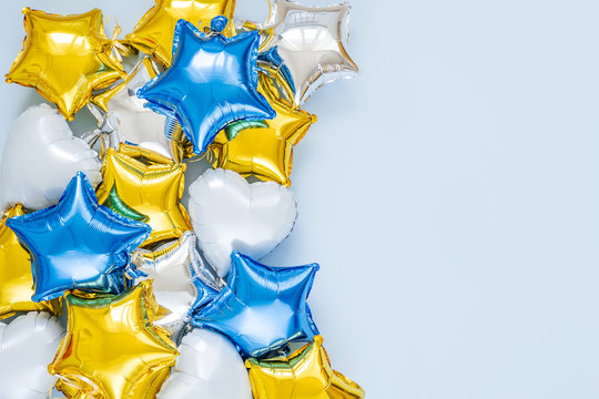 Gold And Silver Foil Balloons Of Star Shaped On Blue Background. Holiday And Celebration Concept. Birthday Day Or Party Decoration. Metallic Air Balloons. Congratulation. Greeting Card.