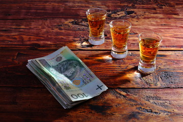 glass of whiskey and money on wooden table
