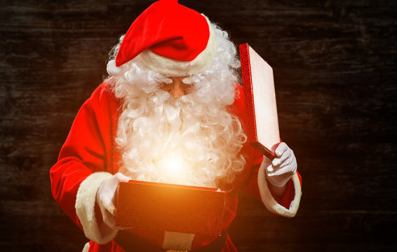 Santa Claus opening a gift box and being invested by a magical light