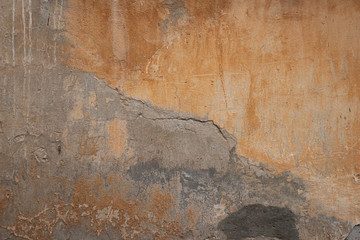 The texture of an old peeling concrete wall painted orange