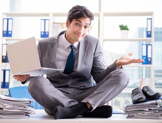 Businessman sitting on top of desk in office