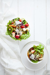 Delicious fruit salad and different fruits on the white table, healthy food concept.