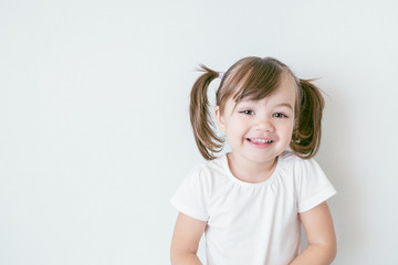 portrait of smiling baby girl with ponytails and in a white t-shirt