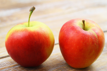 Two red and yellow apples on wooden surface with copy space