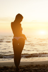 Fototapeta na wymiar Young beautiful girl on the beach at sunset