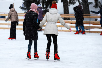 Winter ice rink. The girls in the red skate riding on the ice. Active family sport during the...