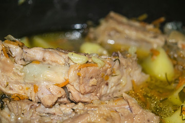 Obraz na płótnie Canvas Stewed pork ribs with potatoes, onions, carrots and dill in a saucepan. Close up. Traditional recipe. Home cooking.