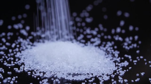 Macro close up of sugar falling to create and form a pile