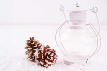 Fototapeta na wymiar White lantern and cones on white snow background, copy space. Christmas concept