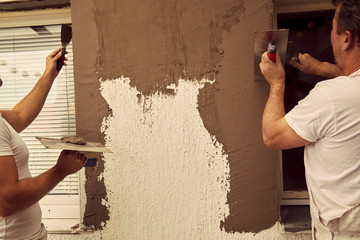 Workers plaster a wall.