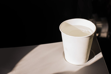 White paper cup of water and headphones on a folding table in an airplane. Drinks on the plane....