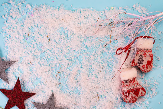 Christmas greeting card with snow branches and mittens on snow blue background View from above